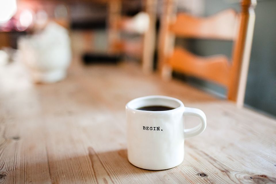 White mug withthe word 'begin' sitting on wooden table